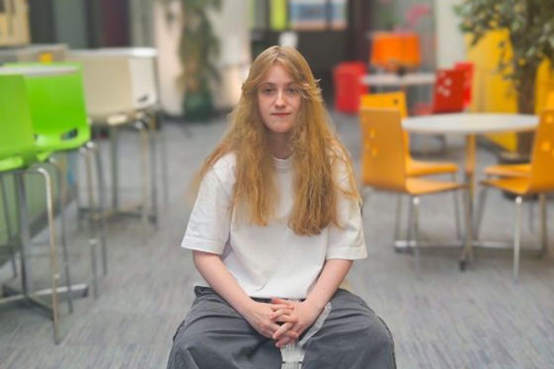 Student Pippa Dunlop sits in a campus building ready to be interviewed on camera